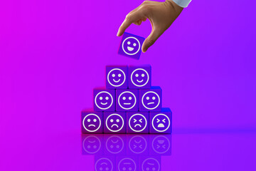 Wooden blocks with icons of faces from happy to sad, a hand picks up a disc with an icon. The...