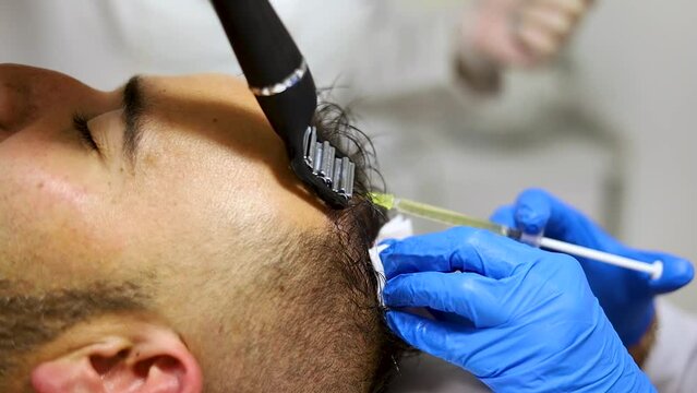 Foreground. man receiving hair treatment in a beauty salon. Man having mesotherapy session in aesthetic clinic, therapist hands in gloves making scalp.PRP injection.