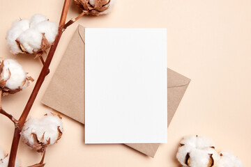 Holiday greeting card mockup with dried branch of cotton flowers and envelop on beige background,...
