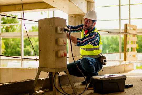 Portrait of skillful electrician who repairing electric box on construction site.