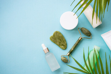 Natural cosmetic product with palm leaves on blue background.