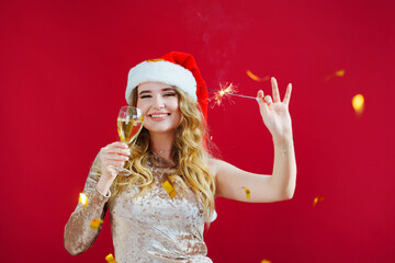 woman in santa hat with champagne and sparklers in red room