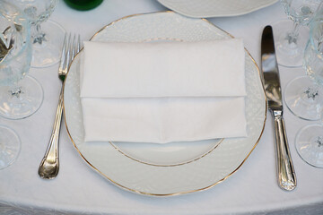 a classic plate with a cloth white napkin and cutlery on the table.