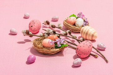 Fototapeta na wymiar Traditional Easter composition - eggs, bird's nests, willow twigs, themed decor. Pink background