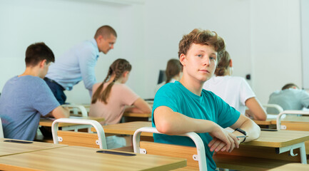 Portrait of young guy student in audience, looking at the camera