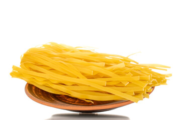 Homemade raw noodles on a clay dish, macro, isolated on white background.