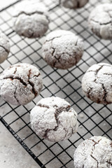 Chocolate chip cookies with cracks. Metallic rack with fresh baked chocolate crinkle cookies in icing sugar on gray textured background