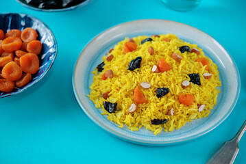 Turmeric basmati rice with dried apricots and prunes and almonds in a plate