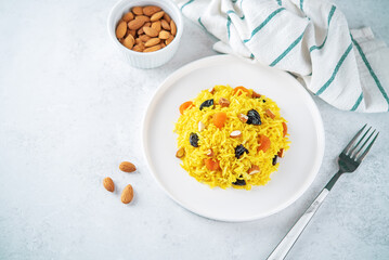 Turmeric basmati rice with dried apricots and prunes and almonds in a plate