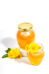 Dandelion jam or honey in the glass jar with fresh dandelion flowers isolated on white background