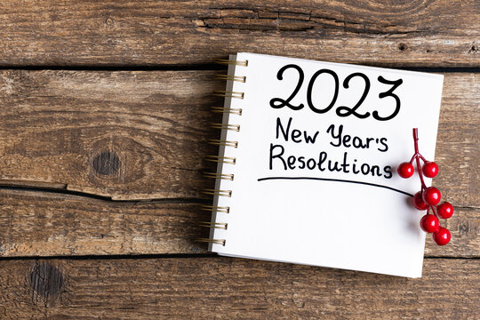 New year resolutions 2023 on desk. 2023 resolutions list with notebook, coffee cup, decorations on table. Goals, resolutions, plan, to do list, action concept. New Year 2023 background. Copy space