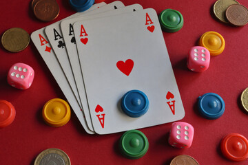 ace cards, playing pieces and chips, dice and coins on a red background