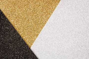 Festive glitter background - abstract geometric composition in golden, black and silver colours with copy space. Minimal fashionable style backdrop. Luxury background