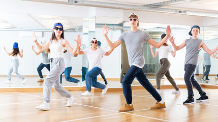 Fototapeta na wymiar Focused teenage hip hop dancers doing dance workout during group class