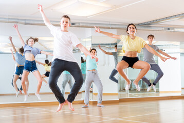 Fototapeta na wymiar Satisfied teenage boys and girls jumping having fun during dance class