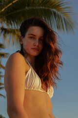 Jolie jeune femme se promenant au coucher du soleil sur une plage de Martinique en pantalon de...