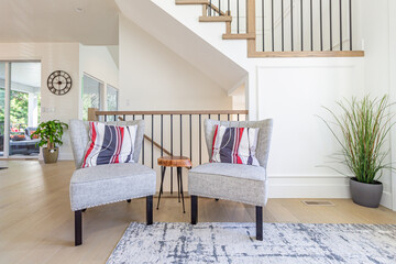 White and grey chair with red and white stripped pillow cushions and an ornate wood stool table...