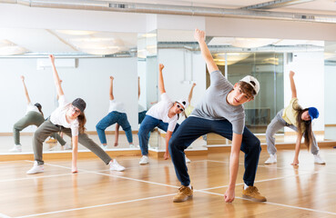 Naklejka na ściany i meble Focused teenage hip hop dancers doing dance workout during group class