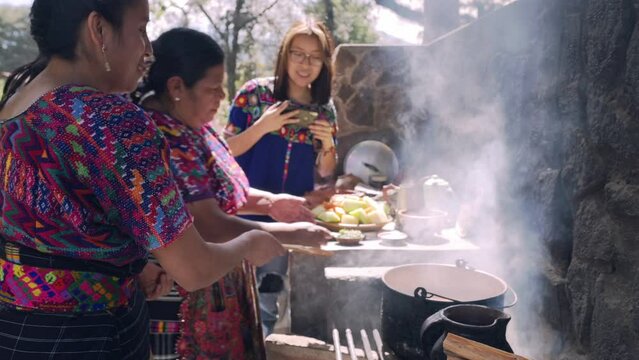 Tres generaciones abuela, madre e hija cocinando. Familia indigena cocinando un platillo tradicional en estufa de leña. 