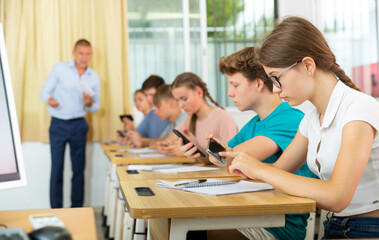Obraz premium Portrait of teen pupils using mobile phones during lesson