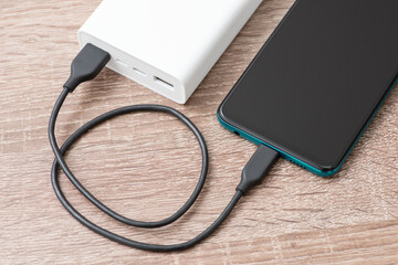 Smartphone battery charging with power bank. close-up. A short cable connects the devices