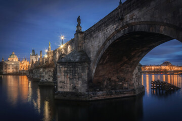View of Charles Bridge over Vltava with statues and National theatre under the arch at night in Prague, Czech Republic