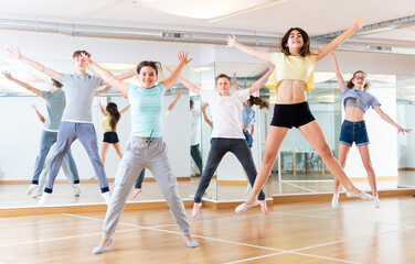 Naklejka na ściany i meble Satisfied teenage boys and girls jumping having fun during dance class