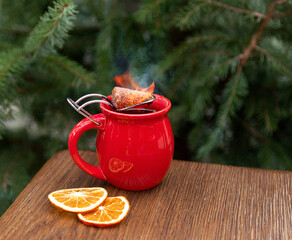 hot mulled wine with a burning piece of sugar on the background of a Christmas tree
