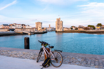 La Rochelle old harbor. Rear view of a bicycle looking at city view while standing on observation point. - obrazy, fototapety, plakaty