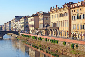 The late afternoon sun shines breightly on apartment buildings along the Arno river in Florence, Italy.