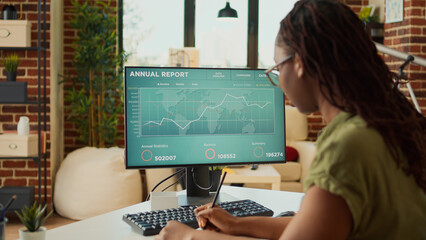 Young adult looking at annual sales report data on computer, analyzing accounting statistics on...