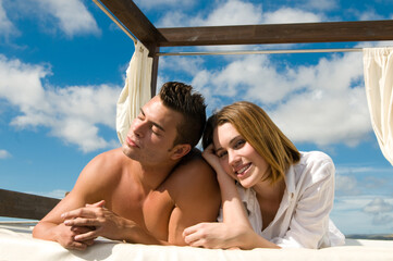 attractive young couple on chill out bed under blue summer sky