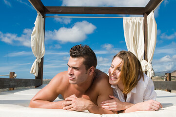 attractive young couple on chill out bed under blue summer sky