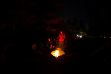 Adventurous athletic men sitting around a campfire, at their camp at night.
