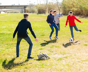 Cheerful teenagers are jogning with ball in spring park