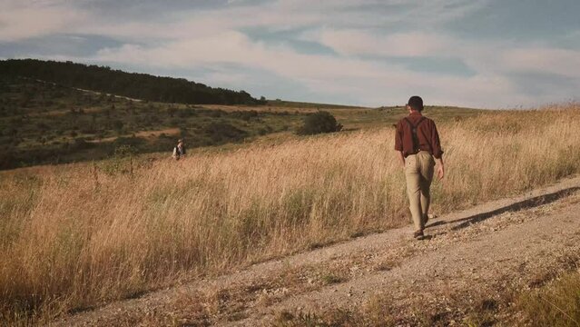 Old adult friends wear vintage clothing in ancient times walking on yellow fields and beautiful views village. Retro style, happy sunny day in village