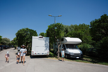 Family near travel RV parking at park,  holiday trip in motorhome, caravan car on vacation. - obrazy, fototapety, plakaty