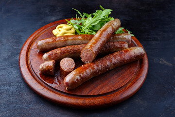 Gebratene Allgäuer Wagyu Rindsbratwurst mit scharfem Senf und Rucola serviert als close-up auf einem rustikalen Holzschneidebrett