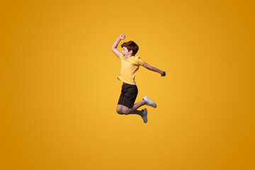 Fototapeta na wymiar Full length photo of little boy jumping isolated pastel yellow color background. Happy people positive emotions. Activity relationship. Smile emotions.