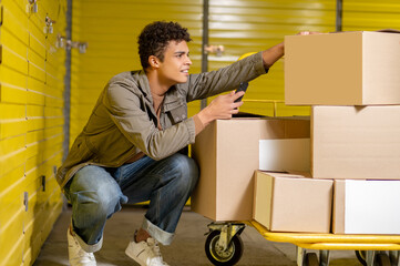 Curly-haired young service man making picture of the boxes