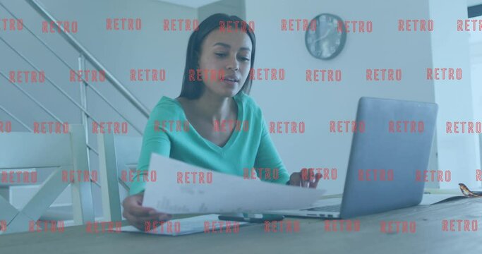 Animation of multiple retro text banners over african american woman holding a document using laptop