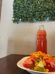 Plato de ensalada gourmet con una botella de limonada sobre una mesa