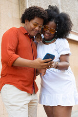 Fototapeta premium Cool people using smartphones. Friends in casual vintage clothes looking at the phone and smiling