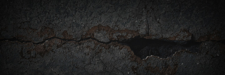 Dark wide panoramic background. Peeling paint on a concrete wall. Dark grunge texture of old cracked flaking paint. Weathered rough painted surface. Patterns of cracks. Darkness background for design.