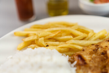 Delicious executive dish of chicken fillet, rice, beans, french fries and green salad with lettuce, tomato and onion accompanied by farofa and vinaigrette. Typical Brazilian food. Selective focus