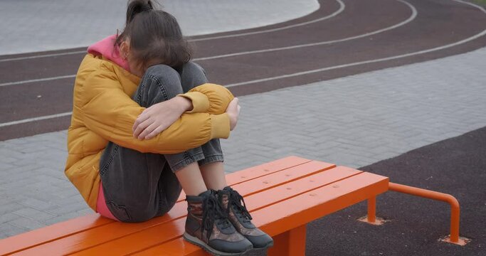 Bullying teenager. A bulled teen girl sits on the playground.