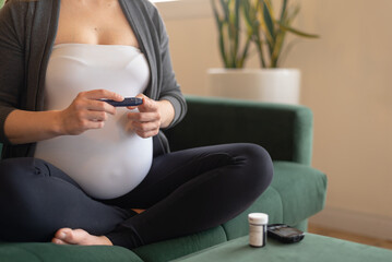Close-up Of Pregnant Woman using lancing device for blood glucose monitoring