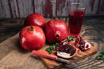 Pomegranate juice in glass,  pomegranates and knife on a cutting board