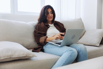 Woman freelancer on day off sitting on sofa with laptop at home online video chat call, smile