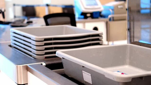 plastic containers for gadgets, hand luggage, bags rides along conveyor to be checked by airport security personnel, boxes on way to X-ray machine airport checkpoint, air travel security requirement